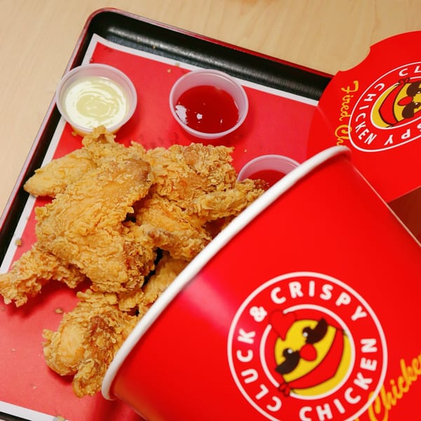 Cluck & Crispy Chicken fried chicken tenders with ketchup and mayonnaise on a red tray.