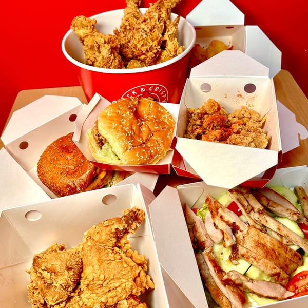 Cluck & Crispy fast-food spread with fried chicken bucket, burgers, nuggets, and grilled chicken salad.